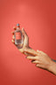 Acqua Colonia Fig & Vetiver Flakon in der Hand vor rotem Hintergrund